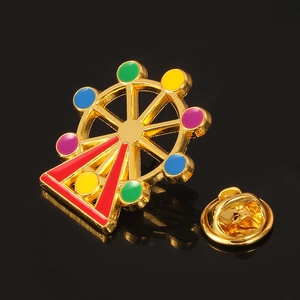 Close-up of golden Ferris wheel enamel brooch with colorful details on black background