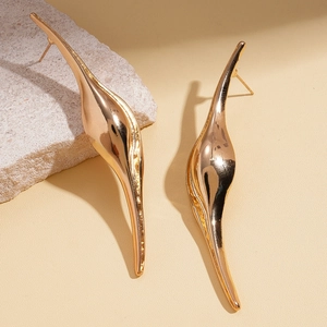Detailed view of long gold streamlined drop earrings with a polished mirror finish