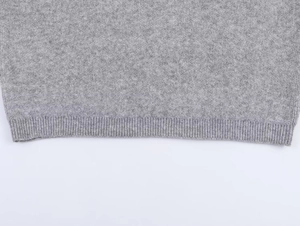 Macro view of gray knit fabric showing the detailed texture and ribbed hem finishing