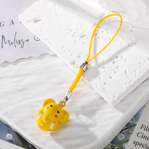 Detailed view of yellow cartoon elephant charm on white marble with woven cord