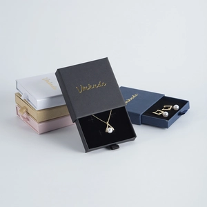 Detail of drawer-style jewelry box with gold logo and elegant ribbon pull handle
