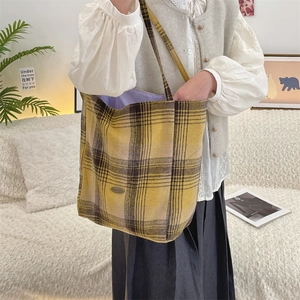 Detail of yellow and black plaid wool tote bag with metal logo and purple lining