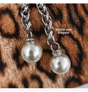 Macro shot of silver chain with white pearls and rhinestone accents on leopard background
