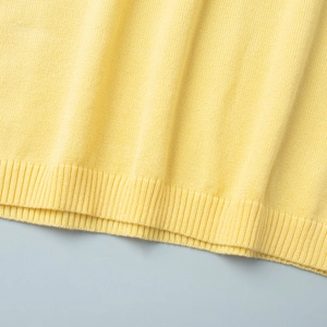 Close-up of yellow knit top hem featuring classic ribbed texture and fine stitching detail