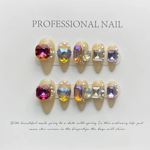 Detailed view of almond-shaped press-on nails with luxury colorful crystals and pearls
