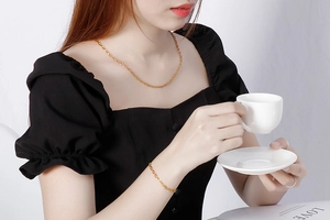 Detail shot of elegant gold chain necklace and bracelet set on a female model