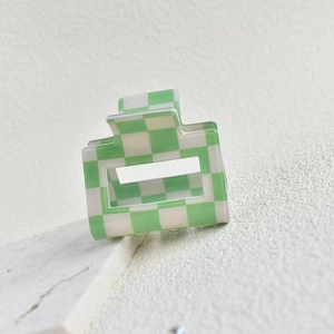 Macro detail of medium acetate checkered hair claw clip in green and white colors