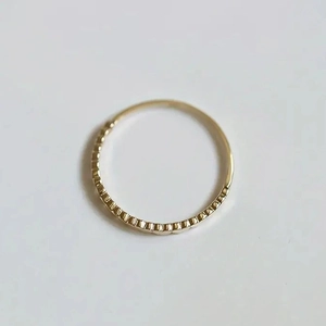 Detailed macro view of gold minimalist ring with faceted texture and smooth finish