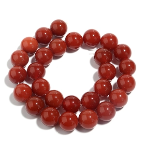 Close-up of polished red agate round beads for DIY jewelry making on white backdrop