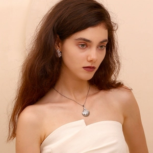 Silver scallop shell necklace and earring set shown on a model with elegant detail