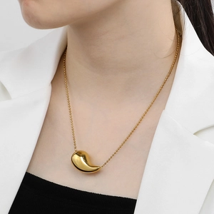 Pendentif goutte doré poli sur un collier à chaîne à boules porté par un mannequin