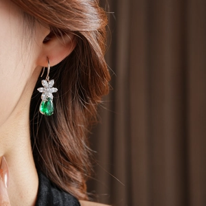 Détail de boucle d'oreille fleur en argent avec zircon goutte verte sur mannequin