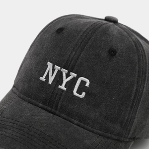 Close-up of white NYC embroidery on vintage washed cotton dark grey baseball cap