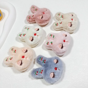 Close-up of plush rabbit charms with embroidered flowers in pink, white, beige and grey