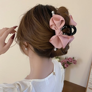 Detailed view of a pink satin bow hair claw clip with rhinestones worn on hair
