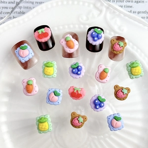Macro detail of strawberry and fruit cookie nail charms on a white decorative plate