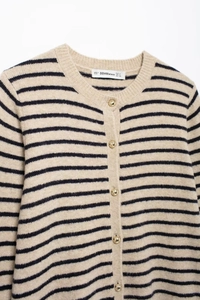 Close-up of the beige and black striped knit cardigan featuring golden metal buttons