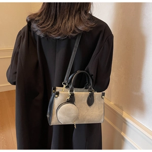 Detail of contrast tote bag with a round coin purse on a model in a black blazer