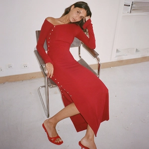 Detail of red off-shoulder knit dress with side buttons and high split sitting pose
