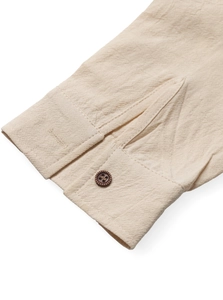 Detail of beige linen long-sleeve shirt cuff with a brown wood texture button