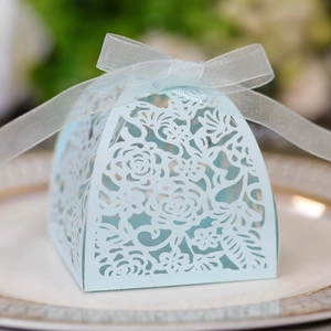 Close-up of light blue laser-cut candy box with floral patterns and a sheer ribbon bow
