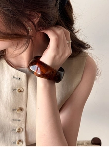 Detail of wide amber resin bracelet with tortoise shell texture on woman's wrist
