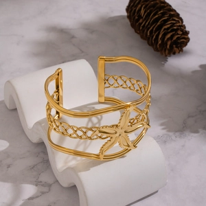 Gold-plated wide open cuff bracelet featuring a textured starfish and woven metal layers