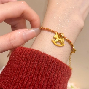 Détail macro du charm cheval à bascule plaqué or 24K avec zircon sur bracelet tressé