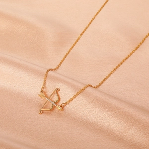 Detail of a gold Cupid's arrow pendant with sparkling zircons on champagne silk fabric