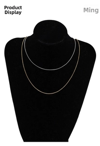 Detail view of thin gold and silver snake chain necklaces on a black neck display