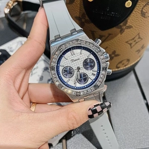 Detail of silver rhinestone bezel watch with grey rubber strap and blue accents