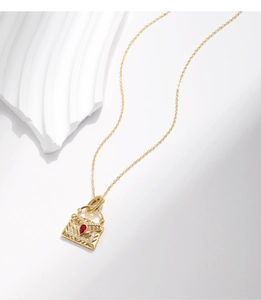 Gros plan du collier avec pendentif sac à main serti de pierres rouges et transparentes