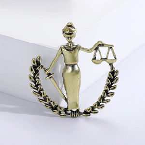 Detail of golden Justice Goddess brooch with scales and sword in laurel wreath