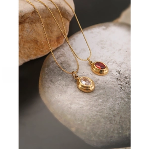 Macro detail of oval red and white zircon pendants on vintage gold titanium steel chains