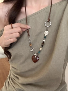Detail of beaded heart pendant necklace on model with vintage wood and stone beads