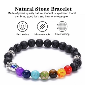 Lava stone chakra bracelet with Hamsa hand and evil eye pendant on white background
