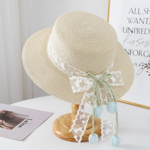 Detailed texture of ivory straw hat with white lace embroidery and green silk ribbon bow