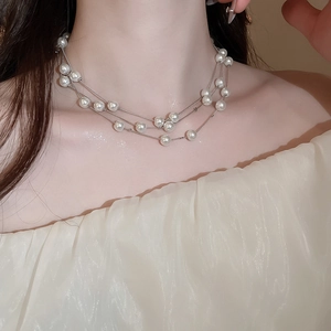 Close-up of model wearing double-layered silver pearl necklace with white off-shoulder top