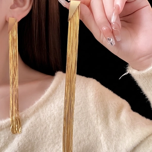Minimalist gold triangle drop earrings with long snake chain tassels on black background