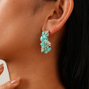 Close-up of Bohemian C-shaped earrings with turquoise stones on a model's ear