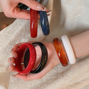 Detailed close-up of colorful resin bangles in amber, blue, and red on a neutral background