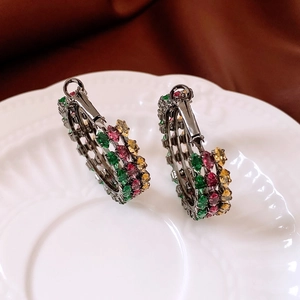 Close-up of vintage multi-color zircon earrings on white porcelain tray with dark background