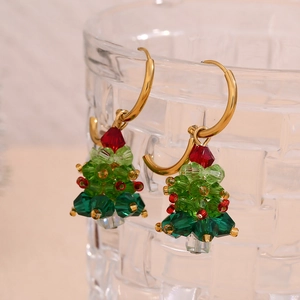 Macro shot of faceted crystal Christmas tree earrings on a textured glass rim