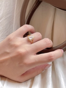 Macro detail of a pear-cut water drop diamond ring with gold finish and pavé halo
