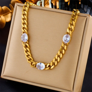 Detail of gold Cuban chain necklace featuring large oval clear gemstones on a jewelry box