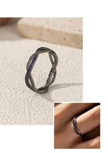 Detail of dark crisscross ring with pavé blue stones on a stone textured background