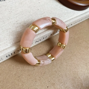 Detail of pink marble acrylic blocks and gold metal spacers on an elastic bangle bracelet