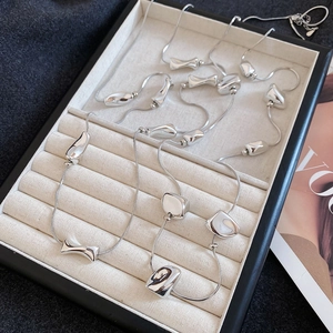 Close-up of irregular silver liquid metal beads on snake chains in a jewelry tray
