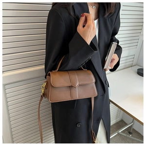 Close-up of a brown leather handbag with elegant handle and shoulder strap details
