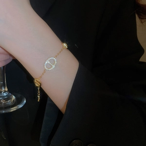 Detailed view of a gold-plated oval chain bracelet with sparkling zircon stones on a model